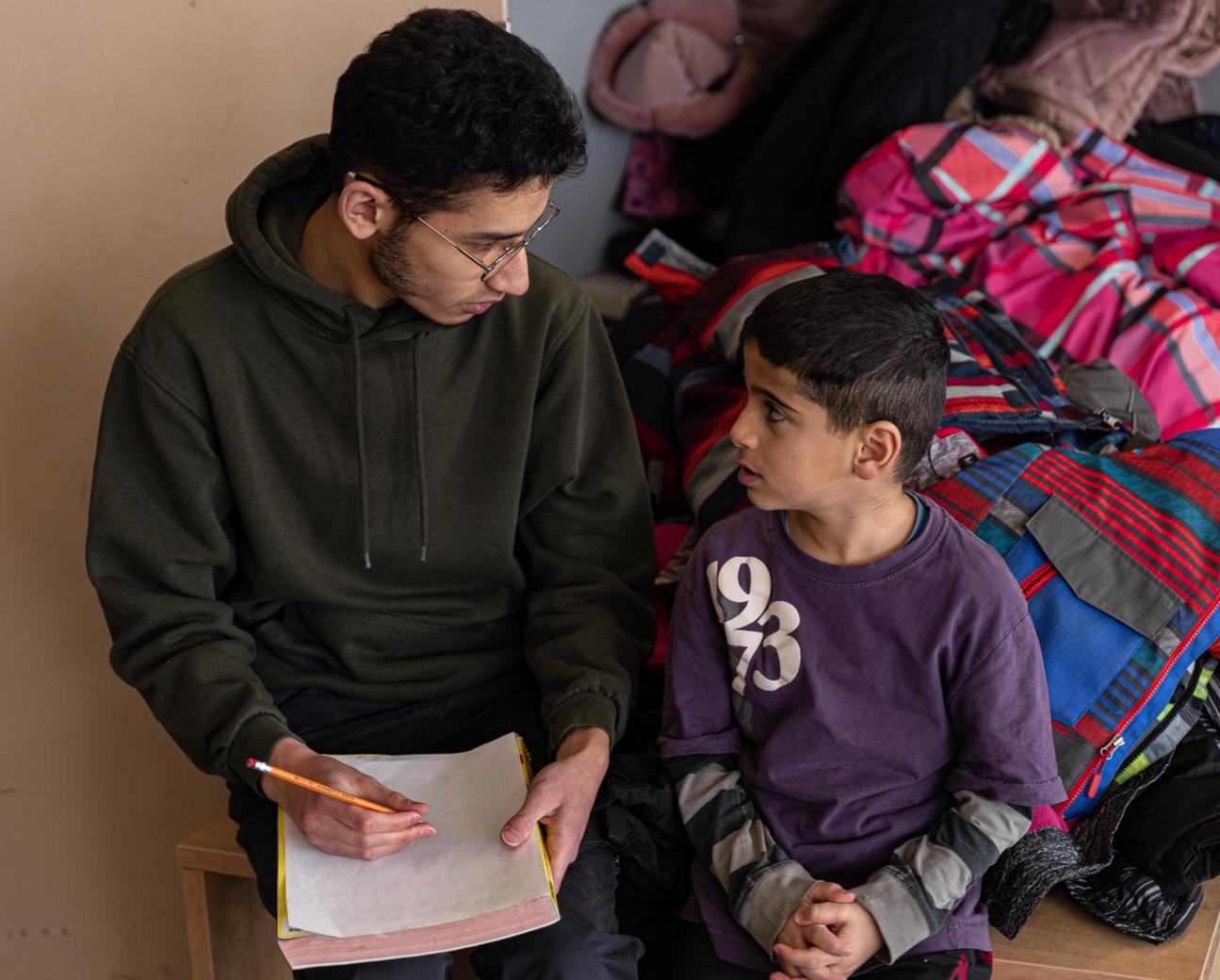 A mentor and child sitting down and looking at notes